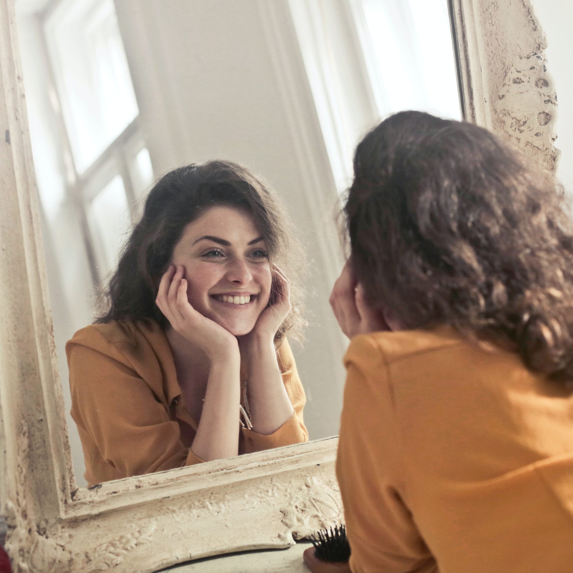 woman smiling in mirror after receiving the aerolase laser for acne treatment